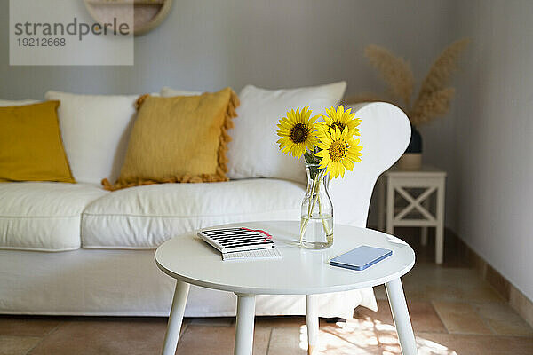 Vase mit Sonnenblumen  Mobiltelefon und Tagebuch auf dem Tisch im heimischen Wohnzimmer