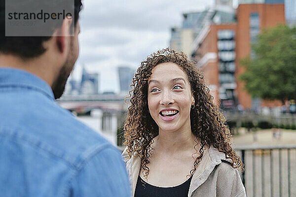 Happy woman talking with man in city