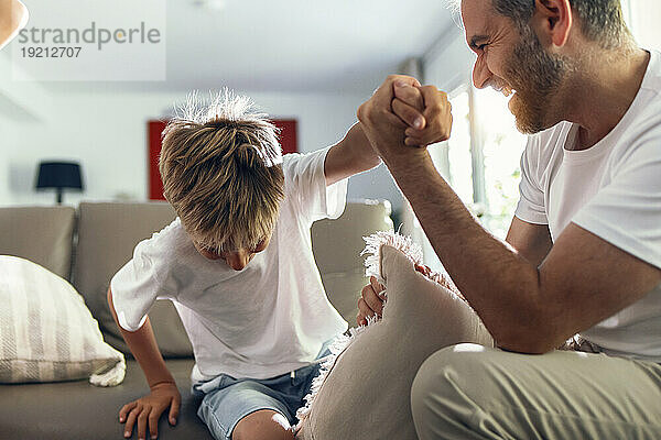 Glücklicher Vater hält die Hand seines Sohnes  der auf dem Sofa sitzt