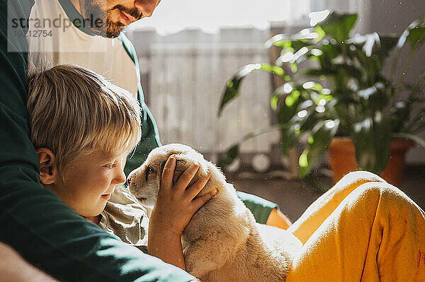Blond boy playing with cute mixed breed puppy at home