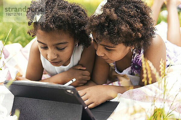 Curious twin sisters using tablet PC in garden