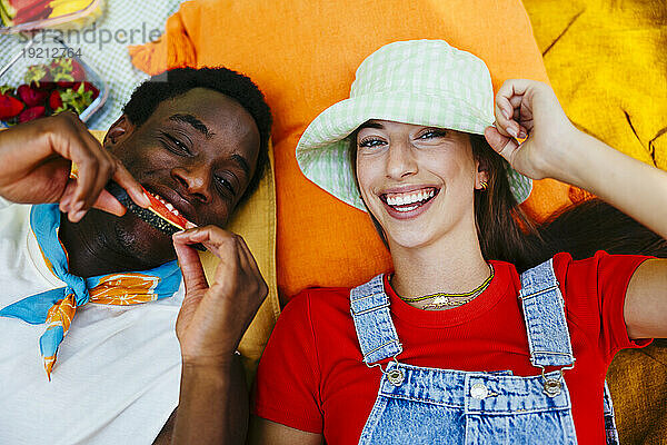 Lächelnde Freunde  die auf einer Picknickdecke liegen