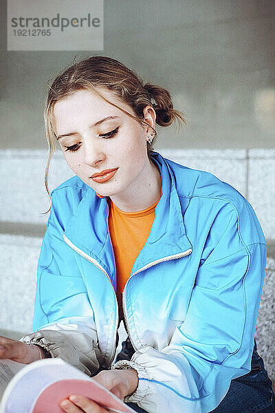 Frau in blauer Jacke liest Buch