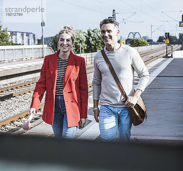 Lächelndes Paar  das gemeinsam auf dem Bahnsteig spaziert