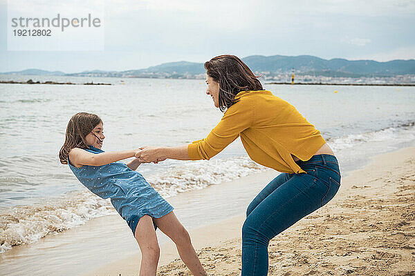 Glückliche Tochter Händchen haltend mit Mutter und Spaß am Strand