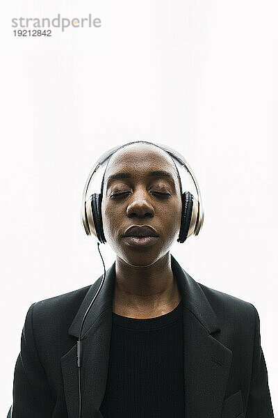 Young woman wearing headphones and standing with eyes closed