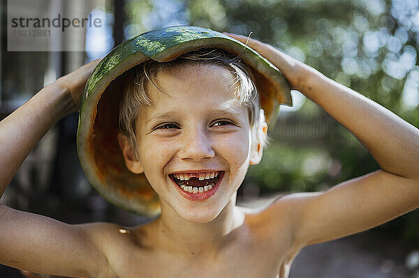 Fröhlicher Junge  der mit einem Wassermelonenhut spielt