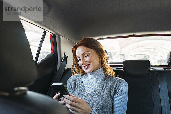 Glückliche Frau benutzt Smartphone im Auto