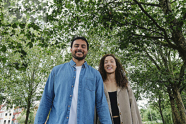 Smiling man and woman walking in park