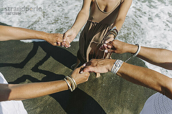 Frauen halten sich am Strand am Meer an den Händen