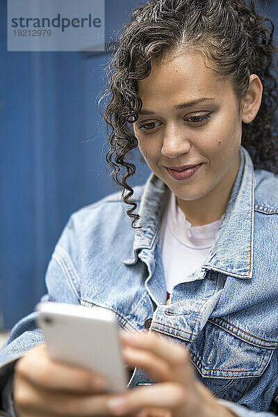 Lächelnde junge Frau  die ihr Smartphone benutzt