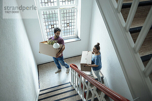 Glücklicher Mann und Frau mit Pappkartons  die die Treppe hinaufsteigen