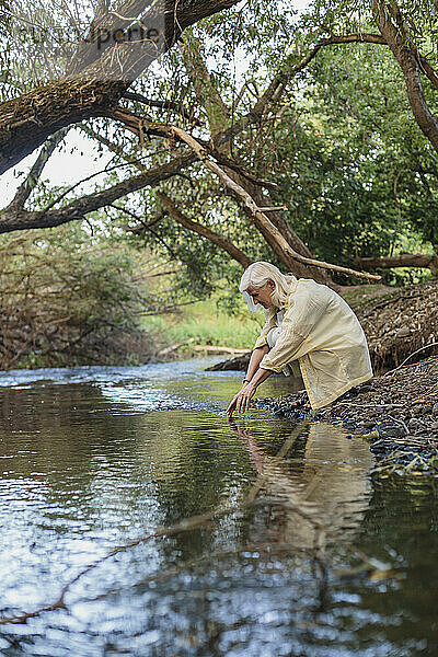 Frau greift im See nach Wasser