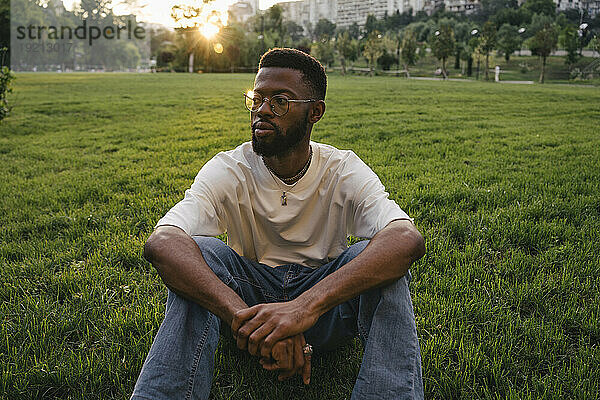Nachdenklicher Mann sitzt auf Gras im Park