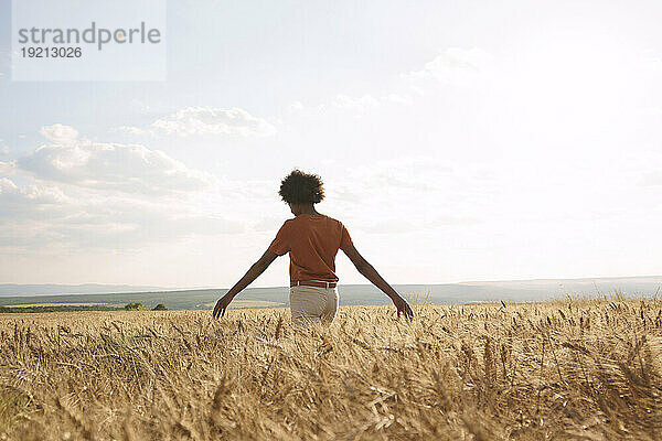 Young woman with arms outstretched enjoying sunset at barley field