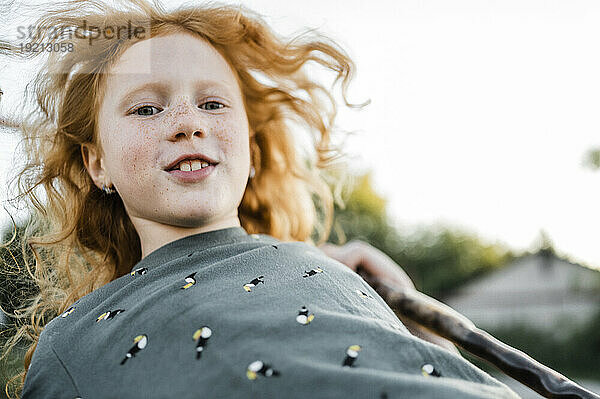 Happy redhead girl swinging in park