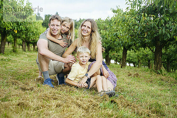 Glückliche Familie bewundert gemeinsam Kirschbäume im Garten