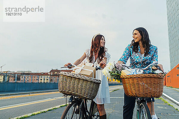 Glückliche Freunde  die bei Sonnenuntergang Fahrrad auf der Straße fahren