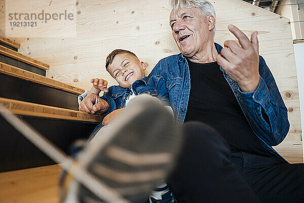 Grandson and grandfather spending leisure time sitting at home