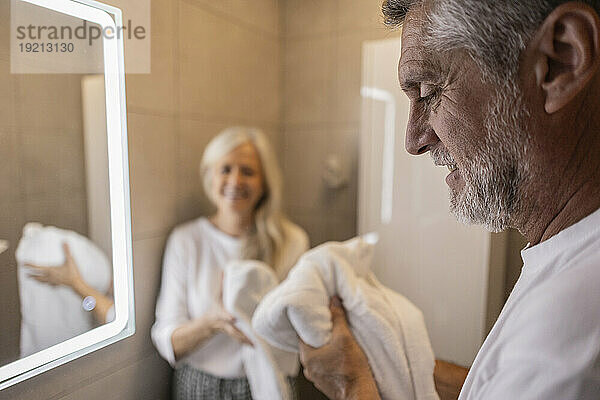 Mann hält Handtuch im Badezimmer zu Hause