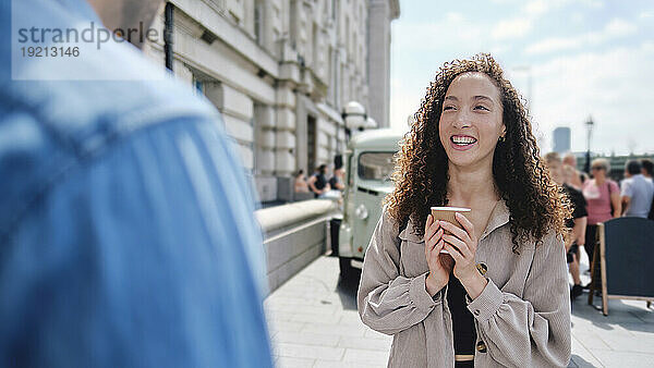 Happy beautiful woman holding coffee cup at street