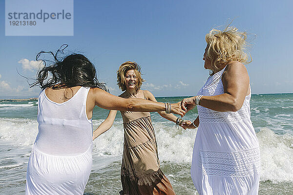 Glückliche Frauen genießen gemeinsam am Strand das wellige Meer