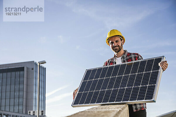 Lächelnder Ingenieur mit Helm und Solarpanel