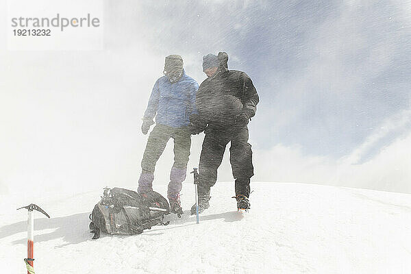 Männer mit Rucksack wandern auf Berg im Schnee