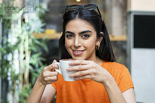 Lächelnde junge Frau genießt Kaffee im Café