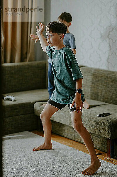 Junge tanzt mit Bruder zu Hause in der Nähe des Sofas
