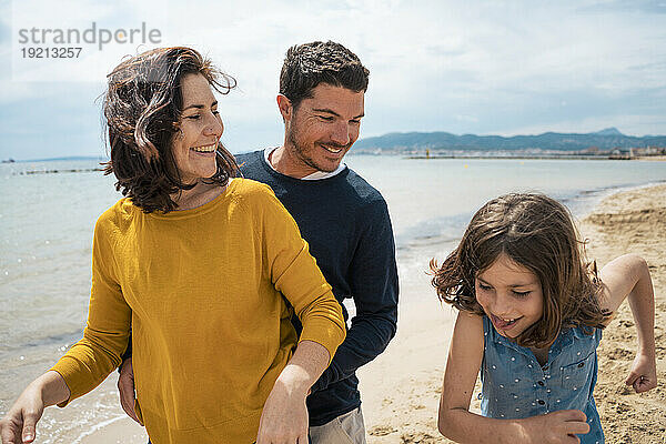 Glückliches Mädchen  das mit Vater und Mutter am Strand genießt
