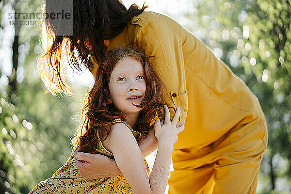 Redhead daughter hugging mother in park