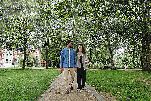 Glückliches Paar redet und geht im Park spazieren
