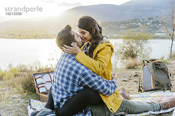 Romantic couple sitting on picnic blanket in front of mountain