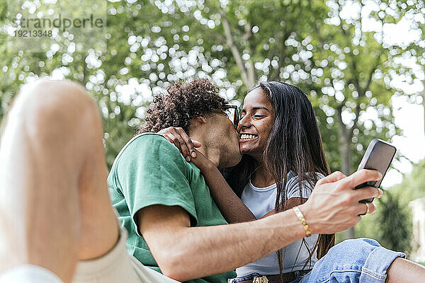 Affectionate boyfriend kissing girlfriend in park
