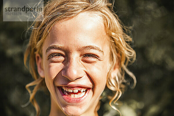 Lächelnder blonder Junge an einem sonnigen Tag