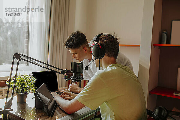 Teenage friends podcasting with laptop and tablet PC at home