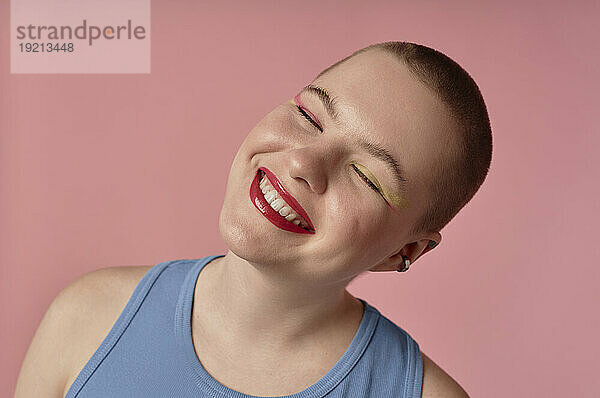 Cheerful woman smiling against pink background