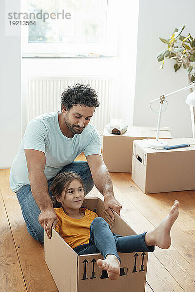 Lächelnder Vater und Tochter sitzen zu Hause im Karton