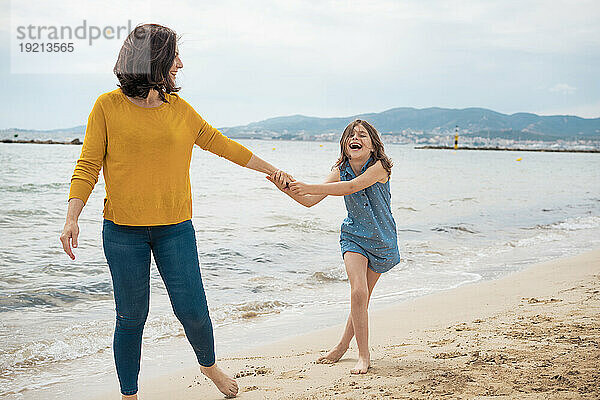 Fröhliches Mädchen spielt mit Mutter am Strand