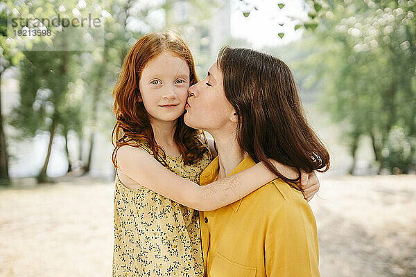 Liebevolle Mutter küsst Tochter im Park