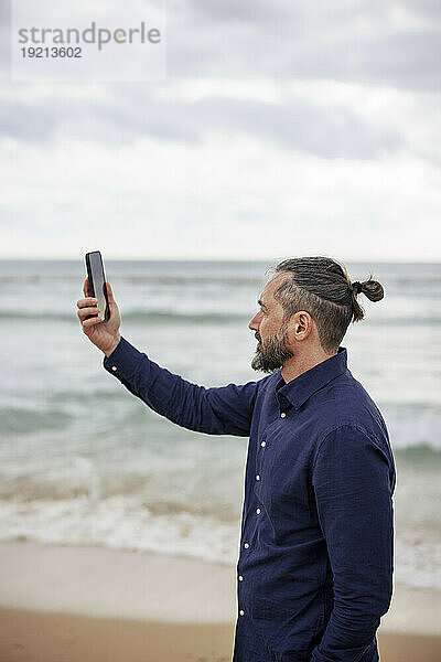 Mann macht Selfie mit Smartphone am Strand