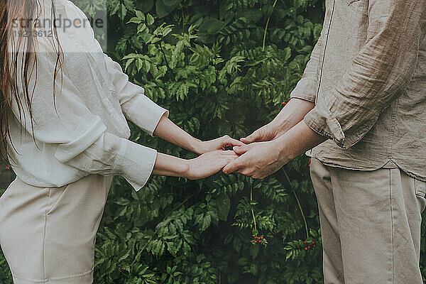 Man and woman holding hands in front of plants