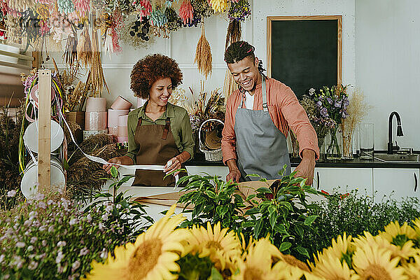 Lächelnde Ladenbesitzer basteln am Schreibtisch einen Blumenstrauß