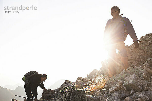 Freunde klettern an einem sonnigen Tag auf einen felsigen Berg