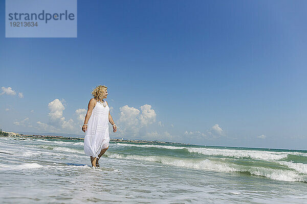 Senior woman walking on shore at beach