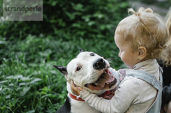 Blondes Mädchen umarmt Hund im Park