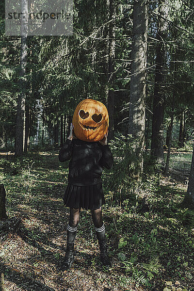 Frau mit Jack O‘ Lantern steht im Wald