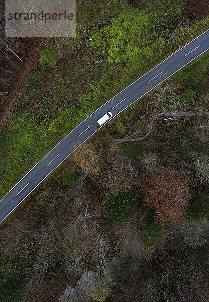 Österreich  Oberösterreich  Drohnenansicht eines Autos auf einer Asphaltstraße  die sich durch den Herbstwald erstreckt