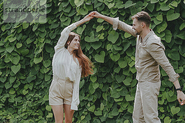 Glückliche Paare tanzen vor Pflanzen im Garten